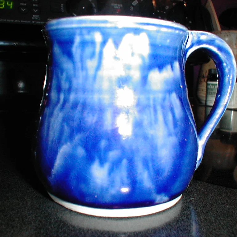 La photo de départ : un mug émaillé bleu sur un plan de travail de cuisine sombre