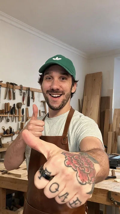 La retouche : la même pose dans un atelier d'ébéniste, tablier de cuir, tatouages et bague gardés