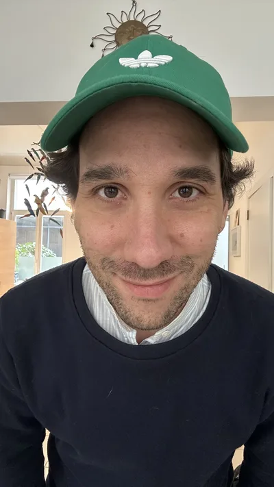 Ma photo de départ : gros plan chez moi, casquette verte, pull marine sur une chemise rayée